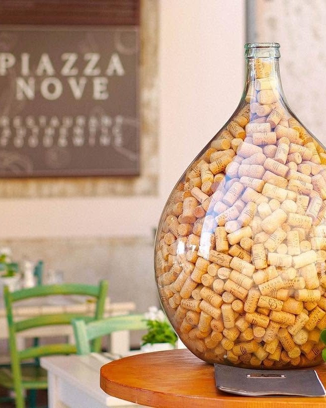 The Piazza Nove sign above a demijohn full of wine corks on the terrace